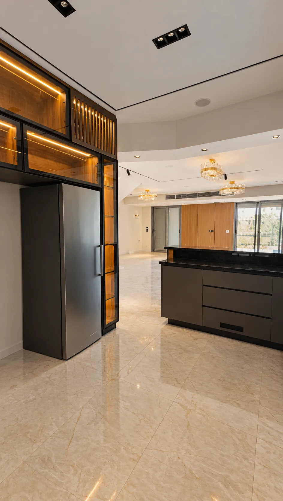Lit wood and glass display cabinets beside the island, with the reception hall beyond.