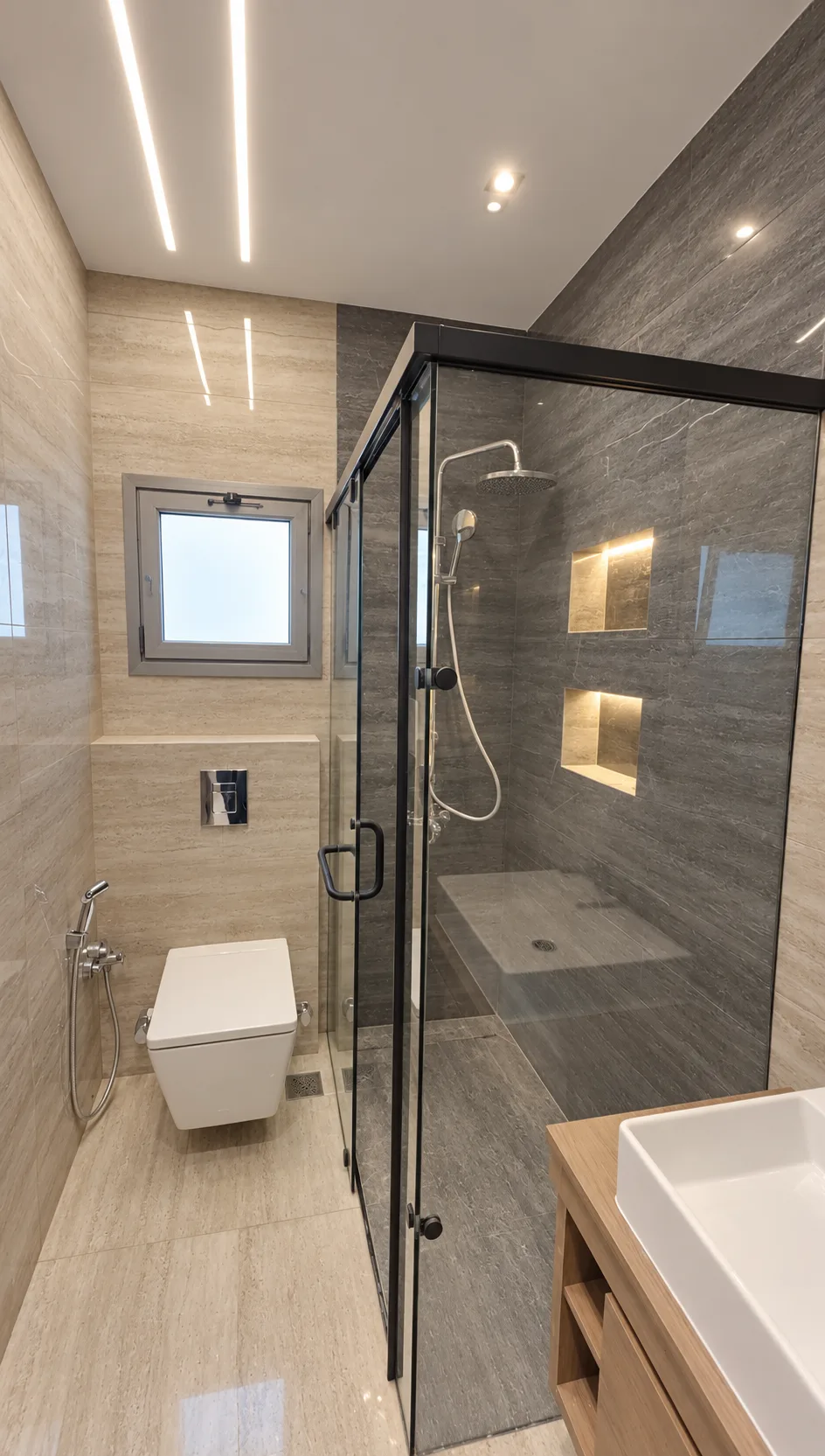 The same bathroom from the vanity: the glass shower, lit niches and a wall-hung toilet.