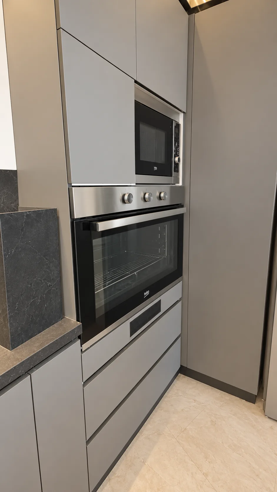 A built-in oven and microwave in grey cabinetry.
